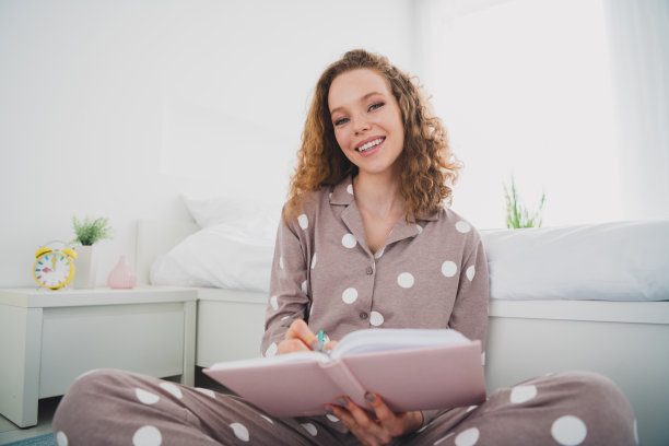 漂亮的年轻女孩的照片写笔记本穿睡衣明亮的室内卧室公寓室内图片下载