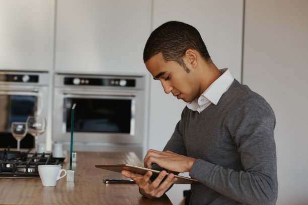 年轻人在现代厨房里浏览电子平板电脑图片下载