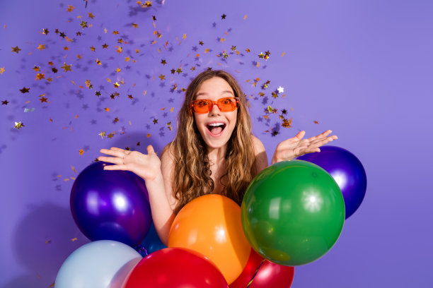 照片中迷人的少女太阳眼镜气球激动五彩纸屑穿着时尚的绿色衣服孤立的紫色背景图片下载