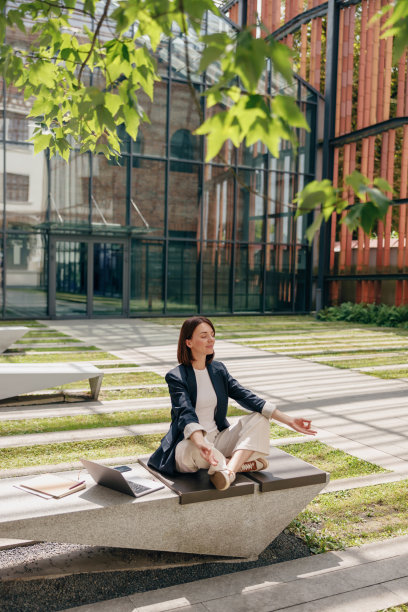 一名女子坐在室外现代办公庭院的长椅上平静地冥想图片下载