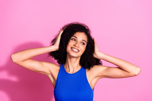 漂亮的年轻女孩的照片肖像看起来梦幻的空白空间触摸头发穿时髦的蓝色衣服孤立在粉红色的背景图片下载