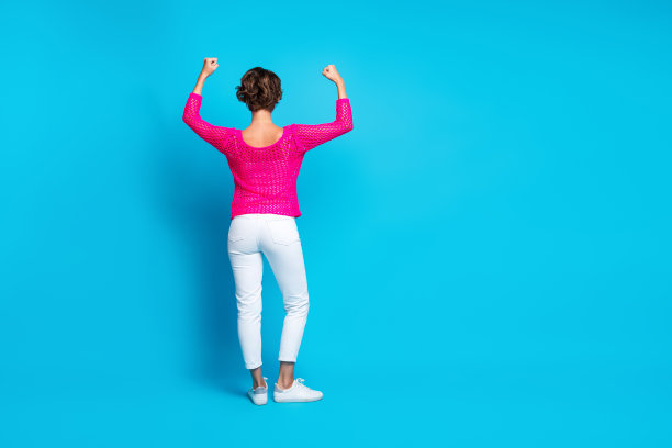 全身照片坚强的冷静的女士穿着粉红色针织衬衫上升的拳头显示力量空的空间孤立的蓝色背景图片下载