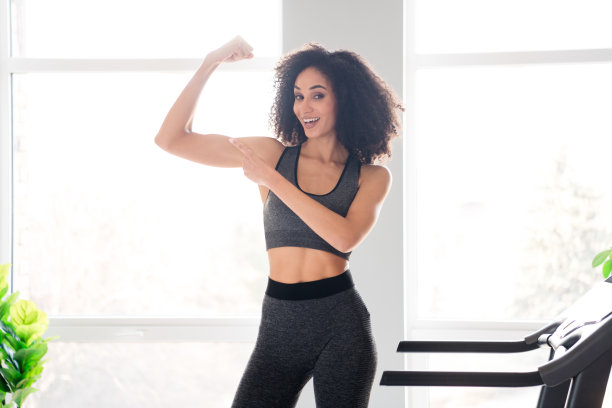 照片可爱可爱的漂亮活跃的女孩教练体育锻炼显示二头肌强壮的手臂白天在室内图片下载