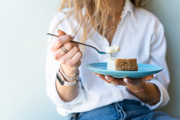 女人用盘子和勺子端着甜点的中间部分图片下载
