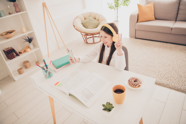 全尺寸照片小可爱的女儿耳机自拍照显示v-sign远程教育家庭教育孤立的室内背景图片下载