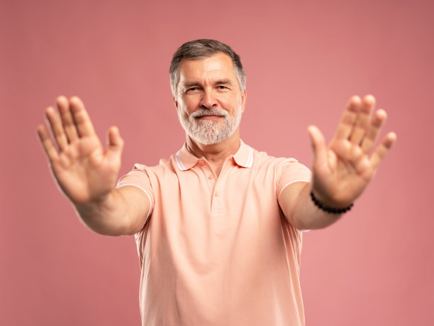 高级商人的肖像，成熟的男人显示停止手势，禁止，站在粉红色图片下载