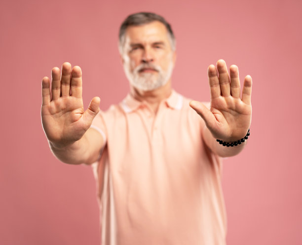 高级商人的肖像，成熟的男人显示停止手势，禁止，站在粉红色图片下载