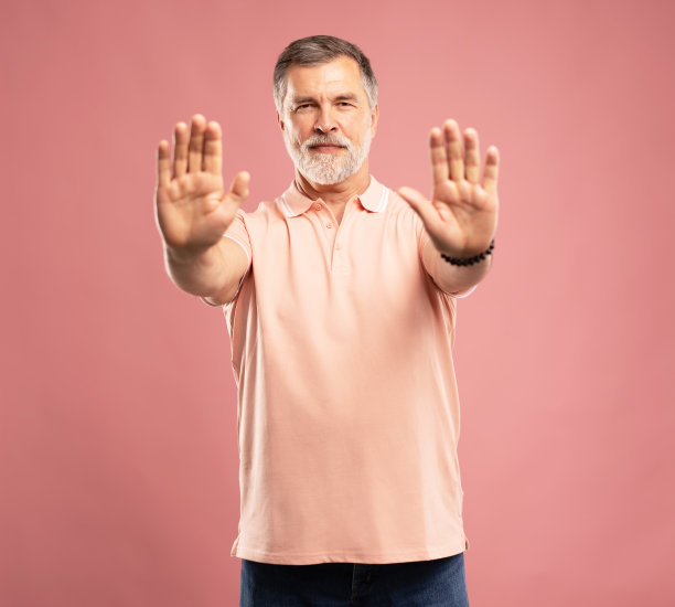 高级商人的肖像，成熟的男人显示停止手势，禁止，站在粉红色图片下载