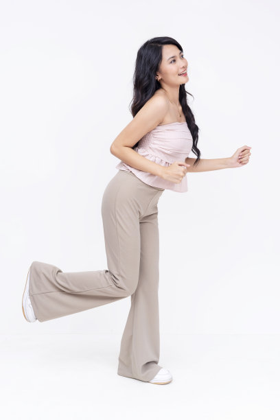 一个年轻的亚洲女人以跑步的姿势开始。一位无忧无虑的女士在赛车。侧视图全身照片孤立在一个白色的背景。图片下载