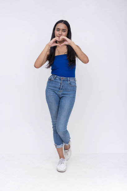 一个年轻漂亮的亚洲女人用双手做一个心形。全身照片被隔离在白色背景上。图片下载