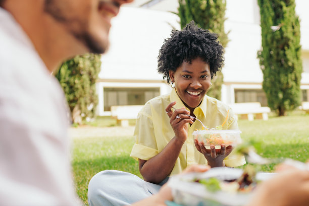 非洲学生和朋友坐在校园草地上吃沙拉的照片。图片下载