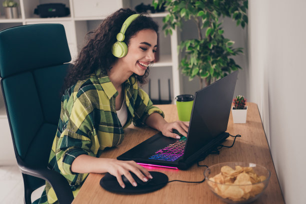 兴奋的甜美女士穿着格子衬衫在室内玩电脑游戏的照片图片下载