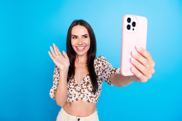 照片开朗可爱的博主女人穿着时尚的衣服视频通话直播hi孤立的蓝色背景图片下载