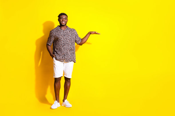 照片中，一个穿着时髦衣服的迷人开朗的男人展示了在充满活力的黄色背景上孤立的空白空间图片下载