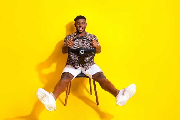 照片中，开朗有趣的疯子穿着时髦的衣服，速度快的汽车，鲜艳的黄色背景图片下载