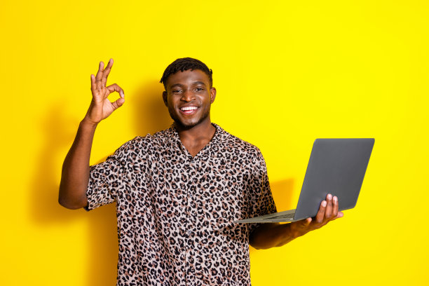 照片中漂亮的快乐男人穿着时髦的衣服，拿着现代设备，黄色背景上孤立的标志图片下载