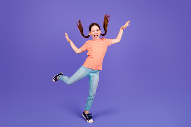 可爱的小女孩跳舞的全身照片好心情有乐趣穿着时尚的红色服装孤立的紫罗兰色背景图片下载