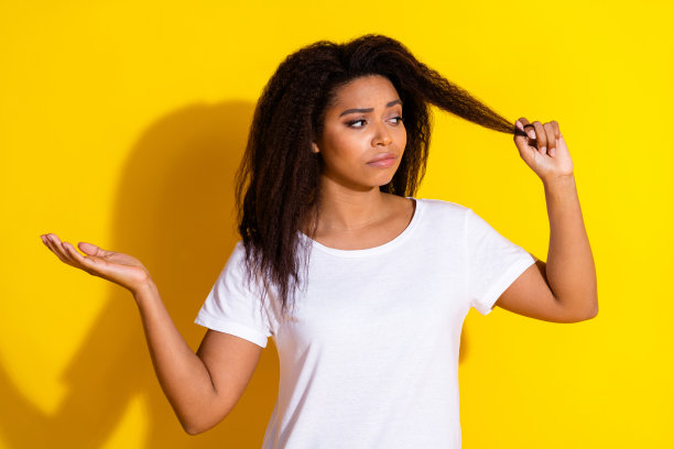 照片中漂亮的年轻女子看起来挽着头发穿着t恤孤立在黄色的背景图片下载