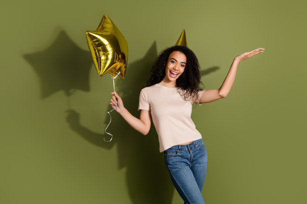 照片好心情的女孩波浪发型穿着米色t恤手持明星气球手掌显示空白空间孤立的卡其色背景图片下载