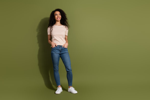 穿着米色t恤牛仔裤的酷女孩的全尺寸照片，手臂放在口袋里，看着销售空白空间孤立在卡其色背景上图片下载