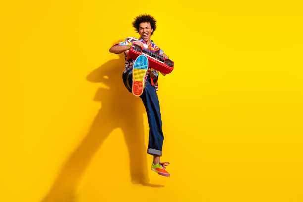 漂亮时髦的年轻人跳音箱的全尺寸照片穿衬衫孤立在明亮的黄色背景图片下载