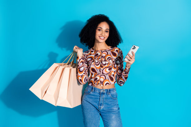 照片可爱的积极的女人穿着时尚的印花衣服，拿着小工具包装，使订单孤立在蓝色背景上图片下载