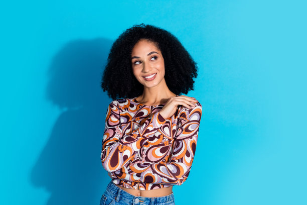 照片中漂亮可爱的美女穿着时尚的印花衣服，在蓝色的背景下看起来空无一物图片下载