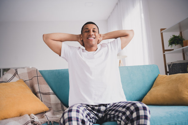 有趣的有吸引力的家伙的照片，睡衣，手臂在头享受周末沙发在室内房间的家的房子图片下载