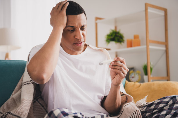 压力抑郁的家伙的照片，睡衣，睡衣，测量温度，度过周末，沙发在室内房间，家里的房子图片下载