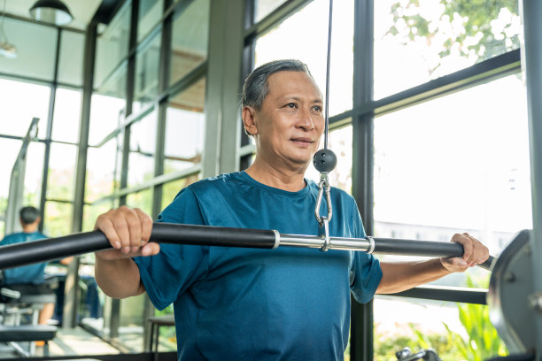老人穿着运动服进行举重训练。亚洲成熟的室内健身馆。健美者身体健康。健身老人在健身房拉杆。图片下载