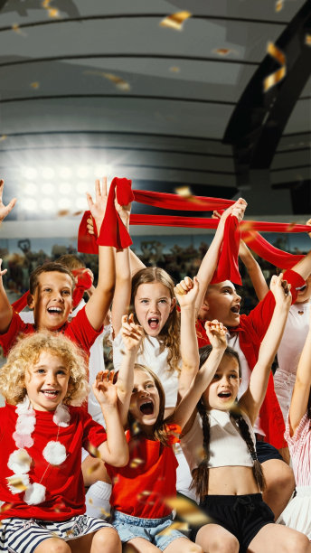 兴高采烈的孩子们穿着红白相间的衣服，热情地挥舞着红围巾，欢呼着，五彩纸屑四处飞扬。庆祝的心情。图片下载