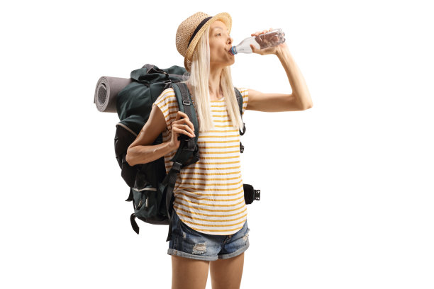 口渴的女游客背着背包从瓶子里喝水图片下载