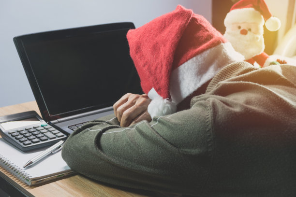 办公室桌子上戴着圣诞老人帽子的男子的后视图图片下载