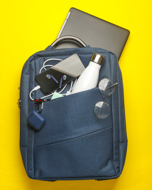 现代小工具和配件的工作和学习在背包黄色背景。前视图。平躺图片下载