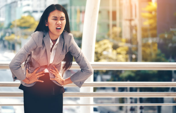 胃痛的女商人靠栏杆站着图片下载