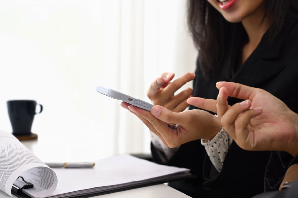 剪短的照片，年轻的女商人微笑着给同事看智能手机上的东西图片下载