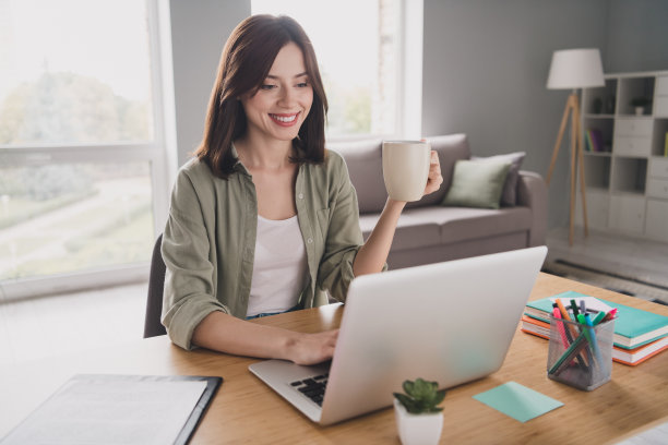开朗的女律师坐在椅子上的照片，手臂拿着热茶杯，用上网本在明亮的办公室里写信息图片下载