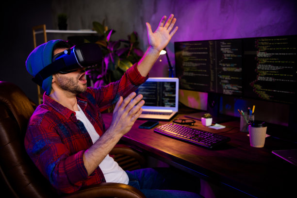 照片微笑有趣的编码员戴着帽子，戴着眼镜，创造视频3d游戏现代小工具在室内工作场所工作站阁楼图片下载