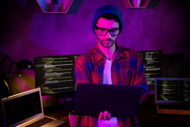 严肃自信的编码员的照片，戴着帽子，戴着眼镜，架着现代设备，在室内工作，工作站，阁楼图片下载