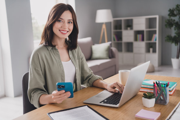 照片快乐漂亮迷人的成功女老板ceo坐在桌子上使用现代的小玩意macbook iphone室内房间工作站图片下载