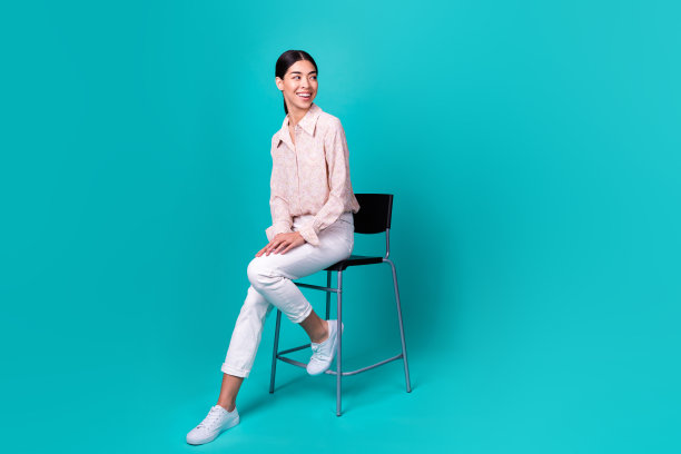 年轻的日本女孩的全身照片坐在看空空间穿着时髦的智能休闲服装孤立的海蓝宝石色背景图片下载