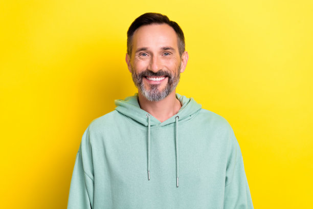 成熟年龄的人的肖像照片男人穿蓝色卫衣运动服牙齿灿烂微笑好的命题孤立在黄色的背景图片下载
