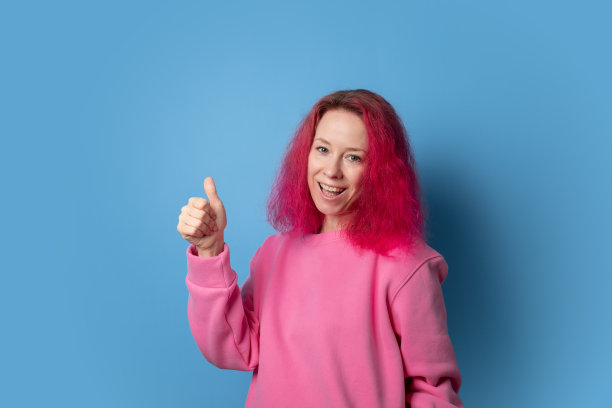 粉色头发竖起大拇指的女人，卷发的年轻学生，表情愉快，风格酷炫。图片下载