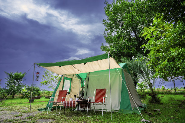 露营帐篷，复古小屋帐篷，古色古香的灯笼，复古的椅子，以及在森林里的木桌上的户外咖啡制作设备图片下载
