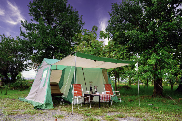 露营帐篷，复古小屋帐篷，古色古香的灯笼，复古的椅子，以及在森林里的木桌上的户外咖啡制作设备图片下载