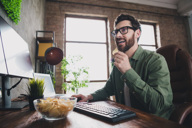 照片的专业it专家年轻人吃芯片电脑桌面阁楼室内办公室室内图片下载