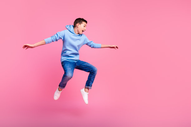 有趣的十几岁的男孩冲浪的全尺寸照片，在粉红色的背景上穿着时髦的蓝色衣服图片下载