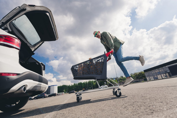 老人的全身照片，把纸袋，食品，汽车，行李箱，购物车，商场，停车场，跳跃，玩得开心图片下载