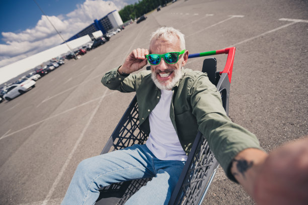 退休老人骑着购物车装杂货车自拍照片太阳镜夏日商场停车场图片下载