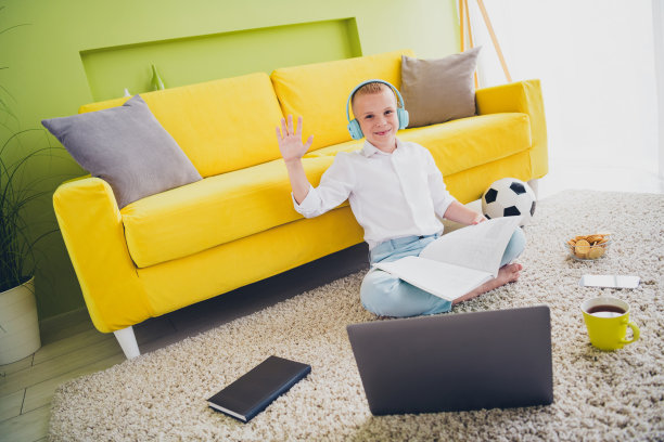 可爱的青春期前男生的全身照片坐在地板上挥手hi耳机看书做作业家庭教育概念学校内部图片下载